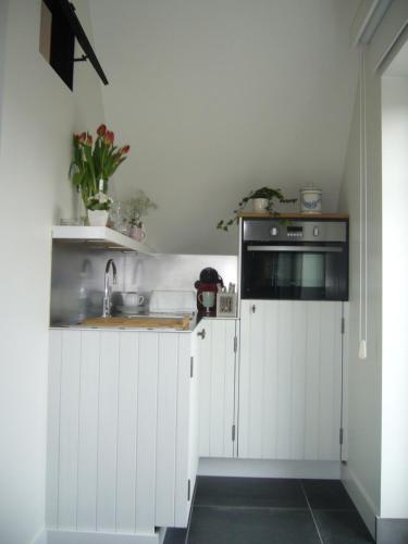 a kitchen with white cabinets and a sink at De Moeraseik in Zele