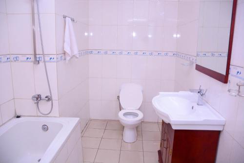 a white bathroom with a toilet and a sink at Beausejour Hotel in Kigali