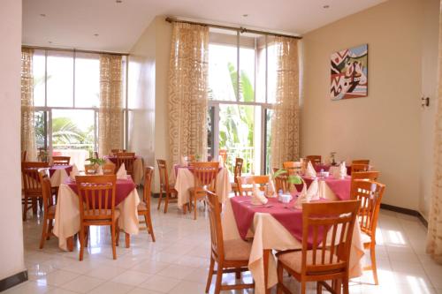 a dining room with tables and chairs and windows at Beausejour Hotel in Kigali