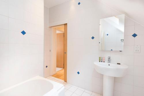 a white bathroom with a sink and a tub at St Paul's by Excel Apartments in London
