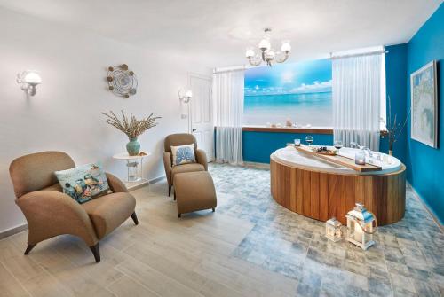 a room with a tub and chairs and a view of the ocean at Gobene Alacati in Alacati