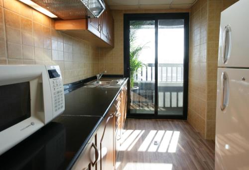 a kitchen with a sink and a microwave at Ramada Hotel & Suites by Wyndham Ajman in Ajman 