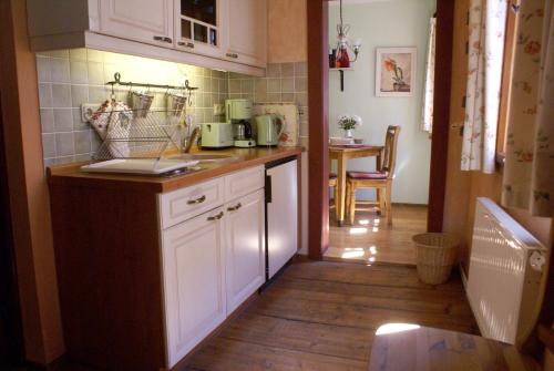 uma cozinha com armários brancos e piso em madeira em Ferienwohnung im Schuhhof em Quedlinburg