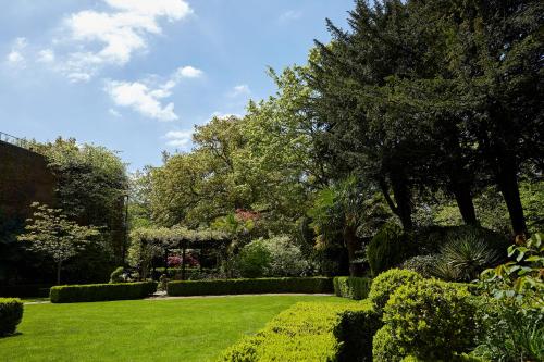 a garden with green grass and trees and bushes at The Bull in Gerrards Cross