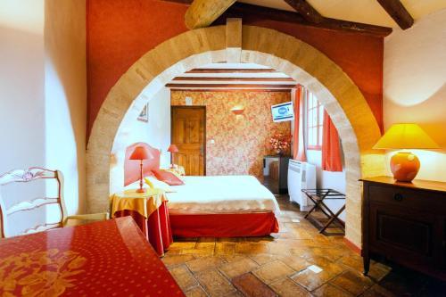 卡布列爾的住宿－L'Enclos des Lauriers Roses，一间卧室设有拱门、一张床和一张桌子