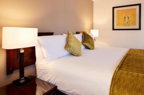 a hotel room with a bed with white sheets and gold pillows at The Bull in Gerrards Cross