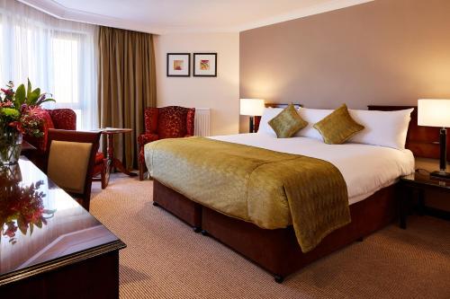 a hotel room with a large bed and a desk at The Bull in Gerrards Cross