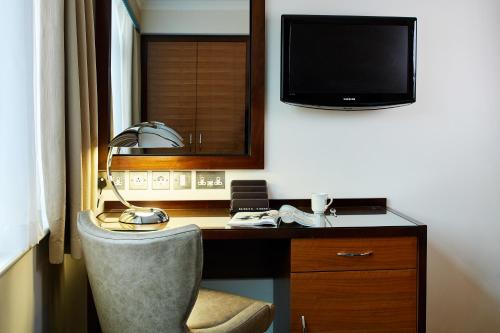a room with a desk with a lamp and a television at The Bull in Gerrards Cross