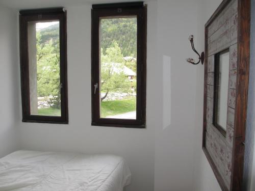 - deux fenêtres dans une chambre blanche avec un lit dans l'établissement L'appart de Serre Che, à La Salle Les Alpes
