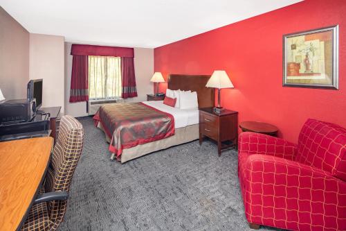a hotel room with a bed and a red wall at Ramada by Wyndham Alpharetta Atlanta North in Alpharetta