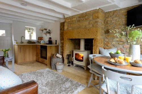a living room with a stone fireplace and a table at Middle Rose in Blockley