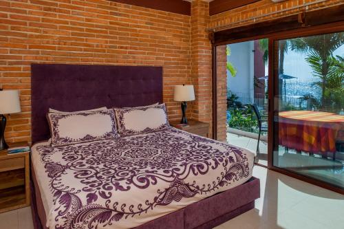 a bed in a bedroom with a brick wall at Vallarta Shores Beach Hotel in Puerto Vallarta