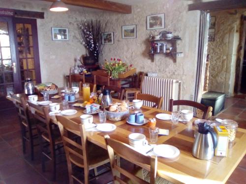 une grande table en bois dans une pièce avec des chaises dans l'établissement B&B La Ferme Aux Fleurs, à Montpeyroux