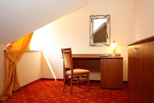 a desk in a room with a chair and a mirror at Hotel Majolika in Modra