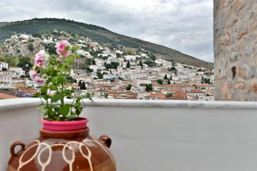 a vase with flowers on a balcony with a city at Kassandra House in Hydra