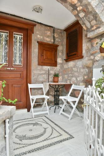 a porch with two white chairs and a table at Kassandra House in Hydra