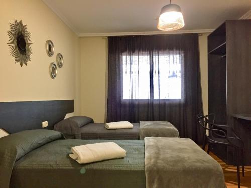 a room with two beds and a window at De Camino vivienda de uso turístico in Arzúa