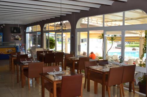 a restaurant with tables and chairs and windows at Apartments Kione Playa Romana Park in Alcossebre