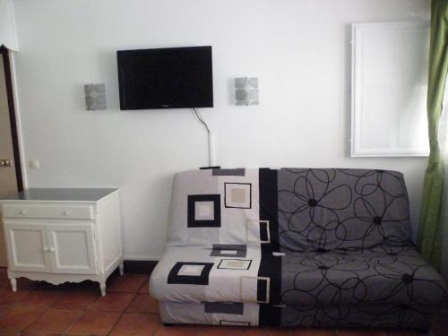 a living room with a couch and a tv on the wall at Résidence Anse des Rochers in Saint-François