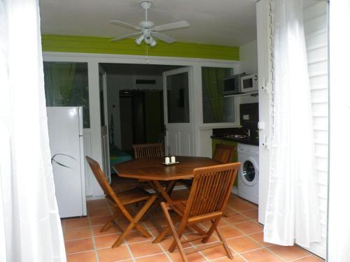 a kitchen with a table and chairs and a refrigerator at Résidence Anse des Rochers in Saint-François
