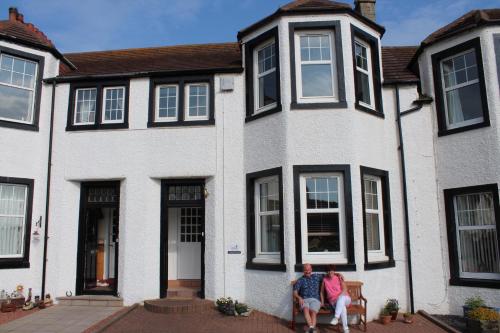 a man and woman sitting in front of a house at No 4 Portpatrick B&B in Portpatrick