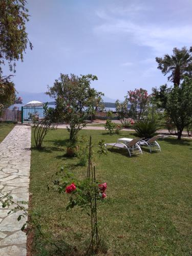 a park with chairs and flowers in the grass at Palmyra Beachfront Studios in Nydri