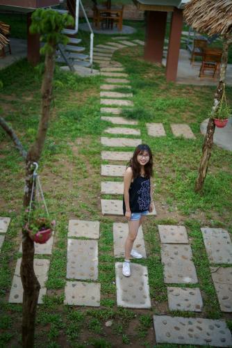 a young girl standing on a path in a garden at Carambola Bungalow in Phong Nha