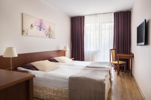 a hotel room with a large bed and a window at Elite Apartments Olymp in Kołobrzeg