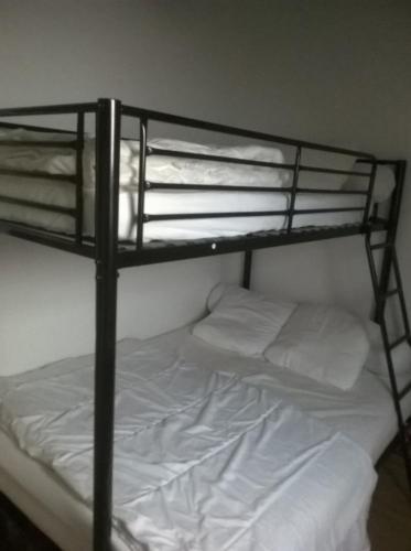 - un lit superposé noir avec des draps et des oreillers blancs dans l'établissement Gite a la Ferme - Baie de Somme, à Saint-Quentin-Lamotte-Croix-au-Bailly