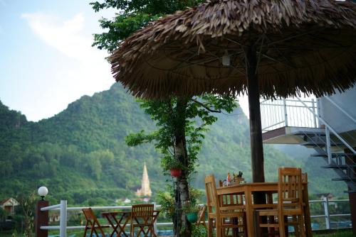 a group of chairs and a straw umbrella with a view at Carambola Bungalow in Phong Nha