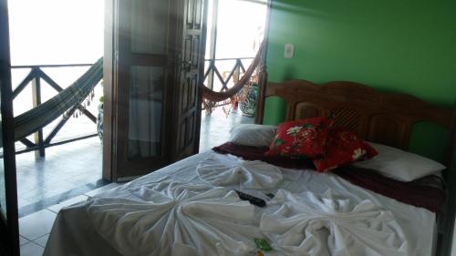 a bed with white sheets and red pillows in a room at Pousada Tranquila in Morro de São Paulo