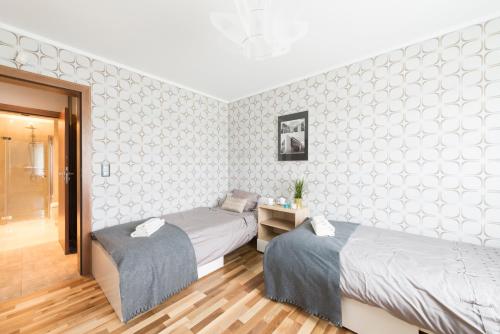 zwei Betten in einem Zimmer mit weißen Wänden in der Unterkunft Apartament Kalinowo Golf - salon z opcją spania, kuchnia i 2 sypialnie, 1-6 osób in Niesulice