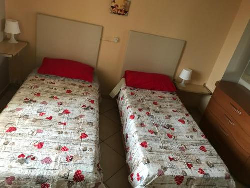 Duas camas com almofadas vermelhas num pequeno quarto em Roy Home em Acerra