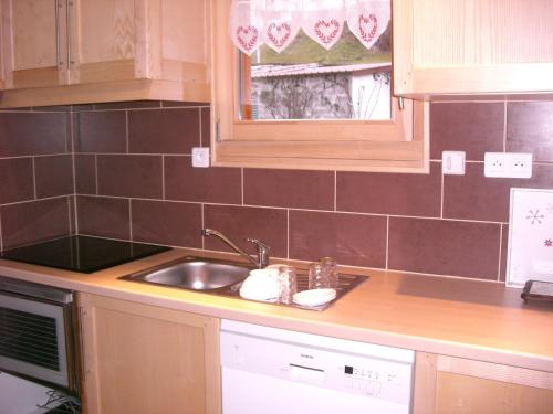 un comptoir de cuisine avec un évier et un micro-ondes dans l'établissement Chalets les Marcels, à La Bresse