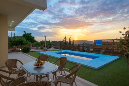 un patio con tavolo, sedie e piscina di Dreamcatcher Villa a Pastida