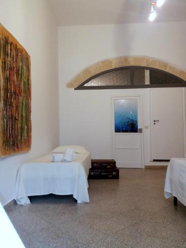 a white room with a bed and a door at La casa di Adele in Syracuse