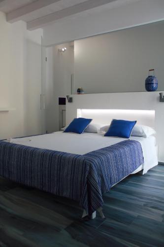 a bedroom with a large bed with blue pillows at Calida B&B in Castellammare del Golfo