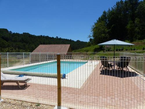 a fence around a swimming pool with an umbrella and chairs at B&B Angueur in Montrem