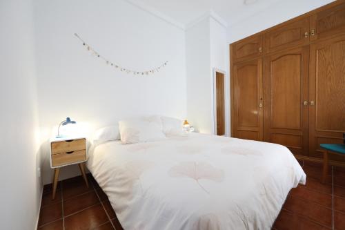a bedroom with a white bed and a wooden cabinet at Cozy Apartment City Hall in Alicante