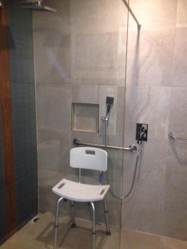 a shower with a white chair in a bathroom at Hit Hoteles Aeropuerto Puebla in Huejotzingo
