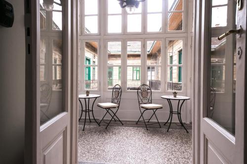 ブダペストにあるOzone Private Roomsの椅子4脚、テーブル、窓が備わる客室です。