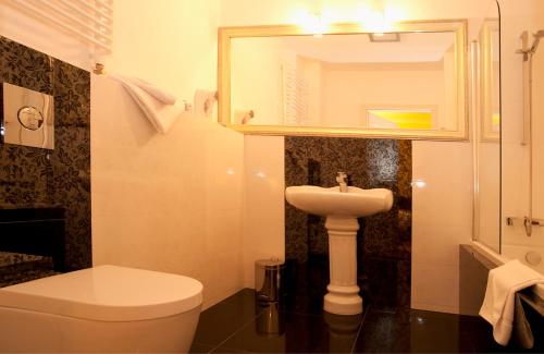 a bathroom with a white toilet and a sink at Hotel Kolegiacki in Poznań