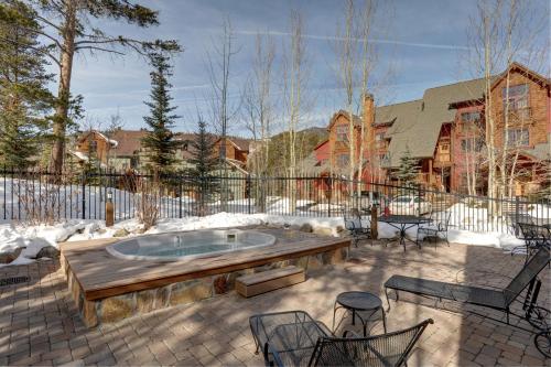 a patio with a hot tub and chairs in the snow at Lakeside Village by Keystone Resort in Keystone
