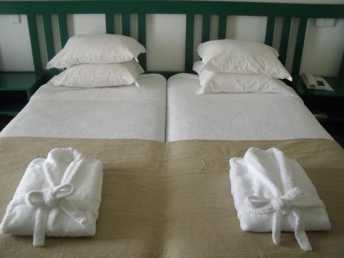 two white towels on a bed with pillows at Hotel Escola in Funchal