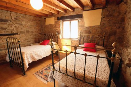 a bedroom with two beds with red pillows and a window at Casa Gorio in San Mamés