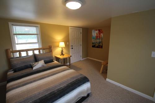 1 dormitorio con 1 cama con lámpara y ventana en Mackinac Lake Trail Motel, en Mackinaw City