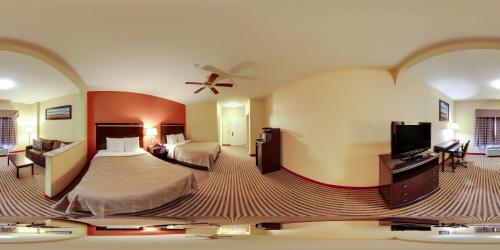 a hotel room with a bed and a flat screen tv at Quality Suites North Houston - Spring in Houston
