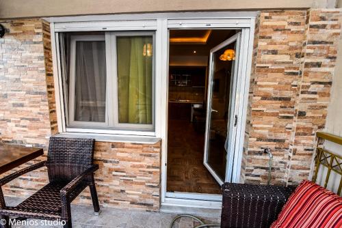 a patio with two chairs and a window at Menios Apartments and Studios in Nea Kalikratia