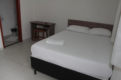 a bedroom with a large white bed and a table at Leati's Hotel in Marília