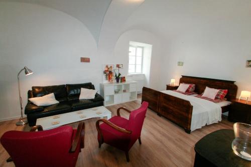 een slaapkamer met een bed en een bank en stoelen bij Galéria Apartman in Veszprém